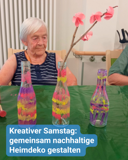 Eine ältere Dame sitzt an einem bunten Tisch mit Bastelutensilien und Dekoration, wahrscheinlich in Gemeinschaft mit anderen Senioren. Bildbeschriftung: Kreativer Samstag: gemeinsam nachhaltige Heimdeko gestalten